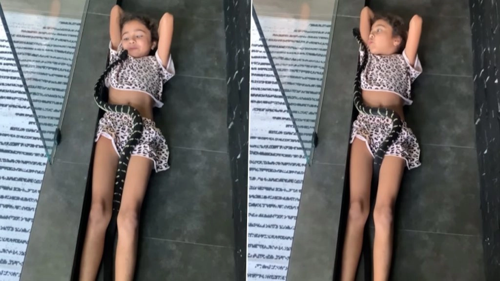 Shocking! काले रंग के खतरनाक सांप के साथ लेटी दिखी बच्ची, लोगों के होश उड़ा रहा है लड़की का बेखौफ अंदाज 